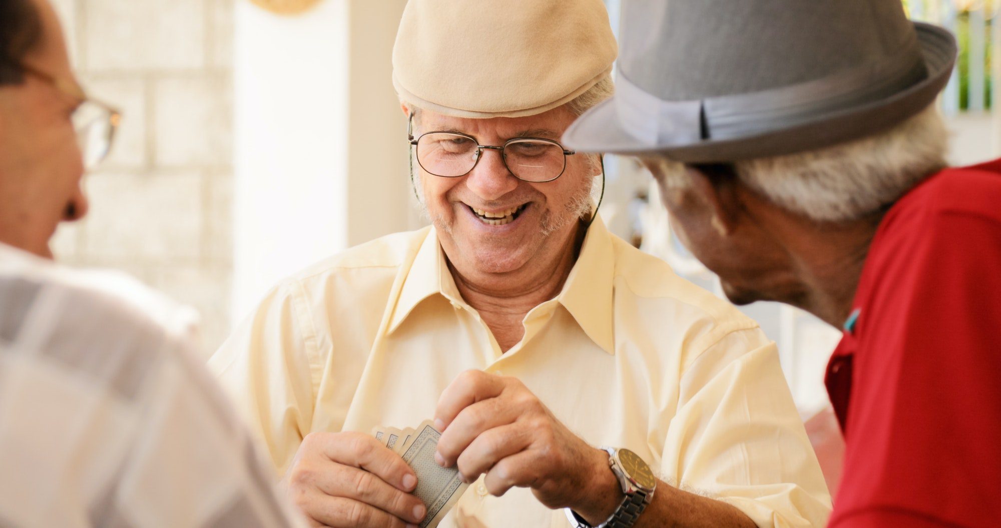 Group of happy seniors playing cards playing cards as they discuss they Medicare Advantage and Medigap plans.