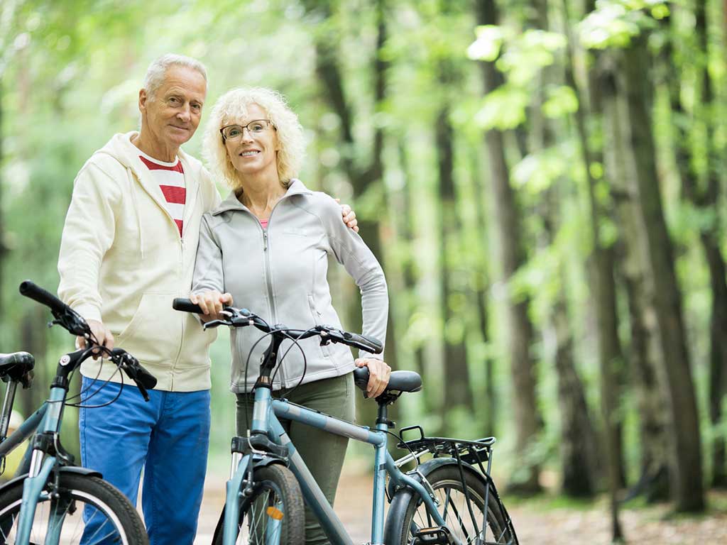 Seniors in the forest riding bikes as they discuss when they are eligible for medicare.