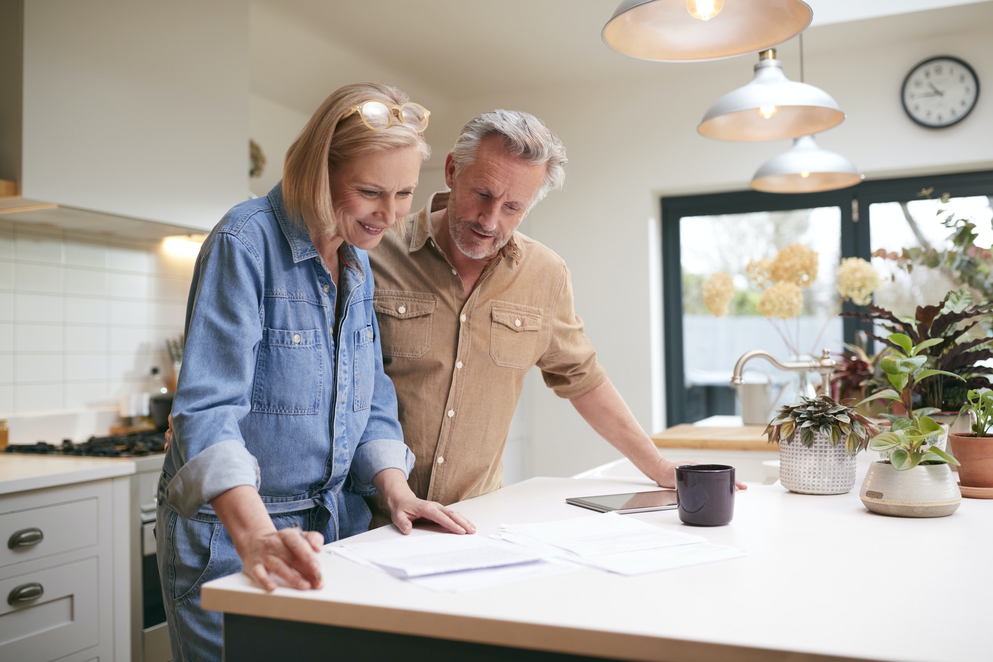 Mature Couple Reviewing Domestic Finances And Investments In Kitchen At Home Together. Medicare and HSA: How to Avoid Excise Tax Penalties