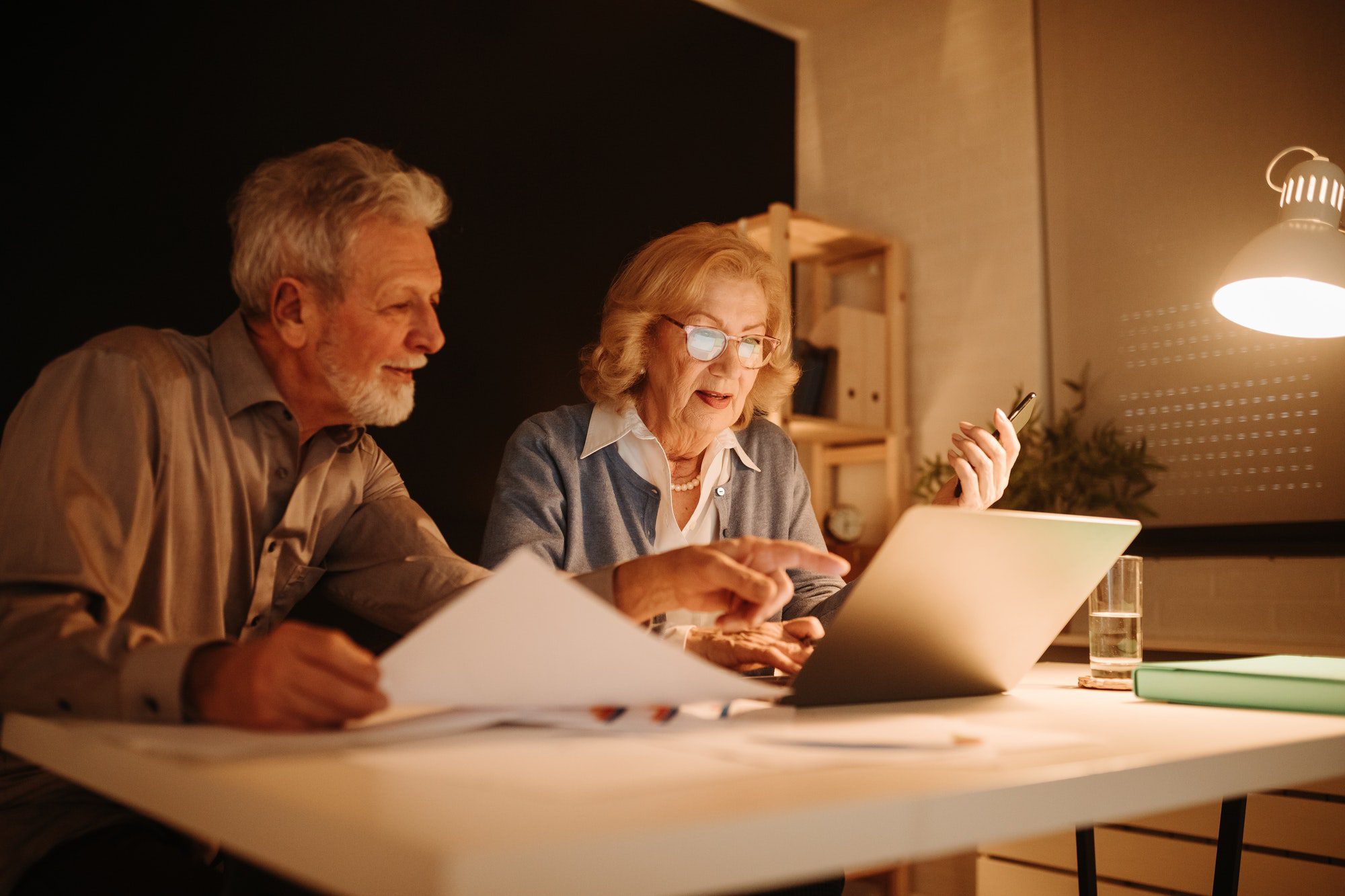 Senior couple is working with laptop late at night in the office. Medicare Enrollment