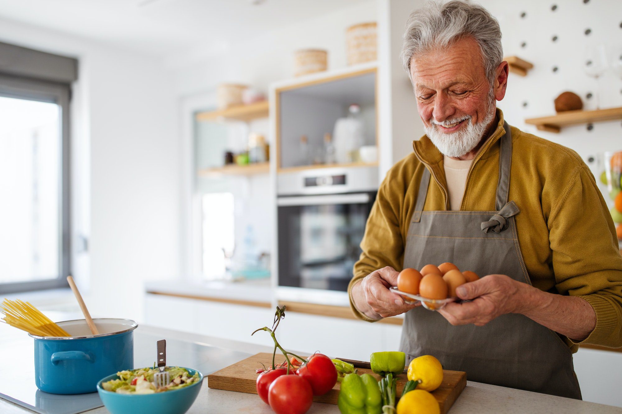 Mature handsome man cooking in home kitchen with Dental Vision Hearing coverage